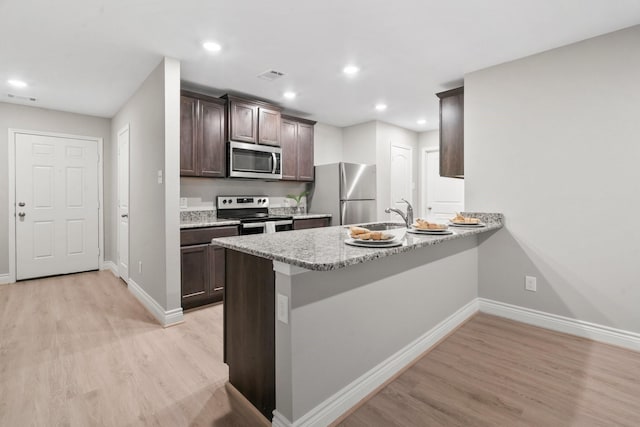 6230 El Cobre Dr, Houston, TX 77048 - kitchen with stainless steel appliances, light wood-type flooring, baseboards, dark brown cabinets, and recessed lighting