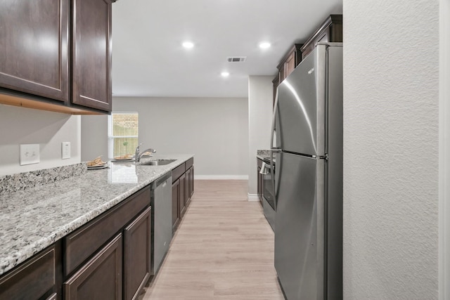 6230 El Cobre Dr, Houston, TX 77048 - kitchen featuring appliances with stainless steel finishes, a sink, dark brown cabinetry, baseboards, and light wood finished floors