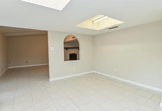 5502 Irish Hill Dr, Houston, TX 77053 - unfurnished room with a skylight, baseboards, a brick fireplace, and light tile patterned flooring