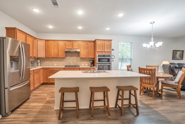 2114 Lost Timbers Dr, Conroe, TX 77304 - kitchen with appliances with stainless steel finishes, a sink, a chandelier, light wood finished floors, and light countertops