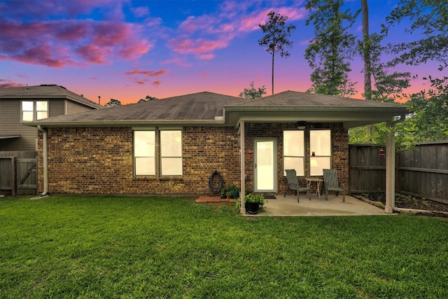 2114 Lost Timbers Dr, Conroe, TX 77304 - back of house at dusk with a patio, brick siding, and a shingled roof