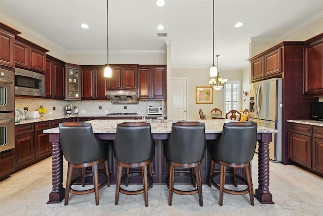 2915 Sentry Oak Way, Sugar Land, TX 77479 - kitchen with stainless steel appliances, a chandelier, a kitchen island with sink, ornamental molding, and pendant lighting