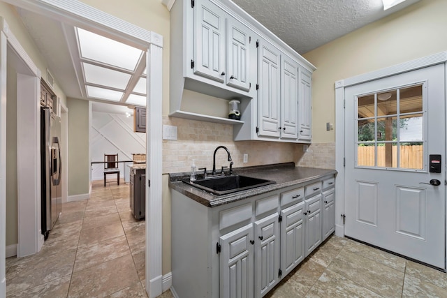 489 Merrimac Park, Conroe, TX 77302 - kitchen featuring a sink, stainless steel fridge with ice dispenser, dark countertops, decorative backsplash, and open shelves