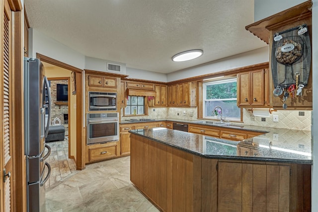 660 Hillcrest Dr, Huntsville, TX 77340 - kitchen with appliances with stainless steel finishes, a sink, a peninsula, brown cabinetry, and tasteful backsplash