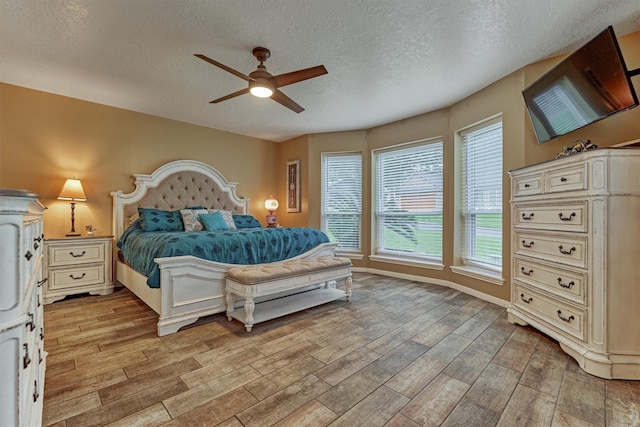 660 Hillcrest Dr, Huntsville, TX 77340 - bedroom with light wood-style floors, a textured ceiling, a ceiling fan, and baseboards
