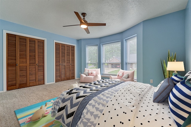 660 Hillcrest Dr, Huntsville, TX 77340 - carpeted bedroom with two closets, a textured ceiling, and ceiling fan