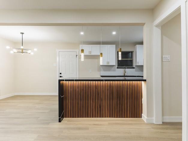 1848 Kipling St, Liberty, TX 77575 - kitchen with light wood-type flooring, a chandelier, white cabinets, baseboards, and backsplash