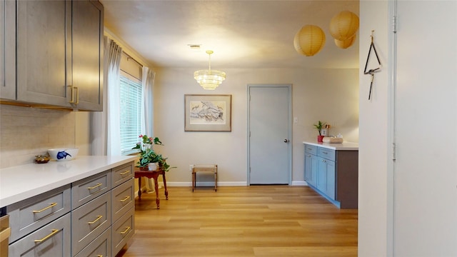 9723 Dalmally St, Spring, TX 77379 - kitchen with light wood-type flooring, backsplash, light countertops, a chandelier, and baseboards