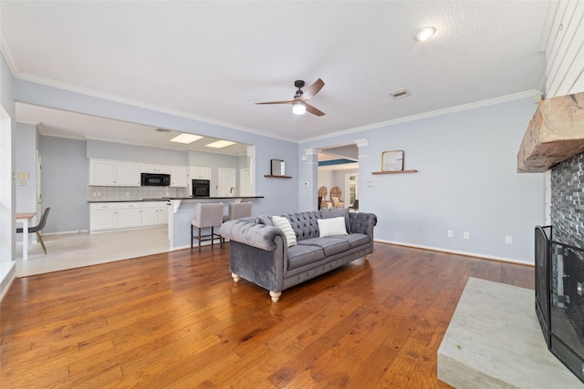 16919 Shady Square Ct, Houston, TX 77095 - living area with a ceiling fan, a multi sided fireplace, light wood-style flooring, crown molding, and baseboards