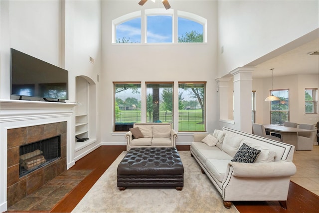 17311 Morgans Lake Dr, Cypress, TX 77433 - living area with wood finished floors, a fireplace, a towering ceiling, a ceiling fan, and baseboards