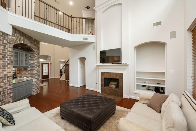 17311 Morgans Lake Dr, Cypress, TX 77433 - living area featuring a towering ceiling, dark wood finished floors, built in shelves, a fireplace, and baseboards