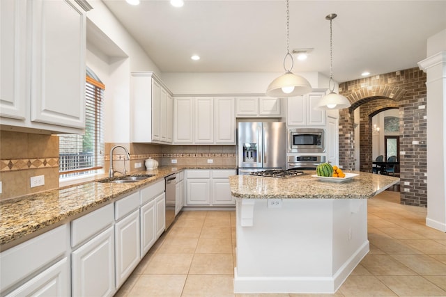 17311 Morgans Lake Dr, Cypress, TX 77433 - kitchen featuring appliances with stainless steel finishes, a sink, arched walkways, light tile patterned floors, and brick wall