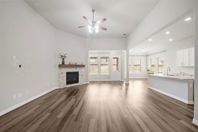 27130 Spanish Wind Ct, Magnolia, TX 77354 - unfurnished living room featuring ceiling fan, dark wood-style flooring, baseboards, recessed lighting, and a glass covered fireplace