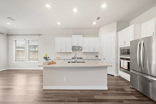27130 Spanish Wind Ct, Magnolia, TX 77354 - kitchen with appliances with stainless steel finishes, under cabinet range hood, light countertops, dark wood-style floors, and recessed lighting