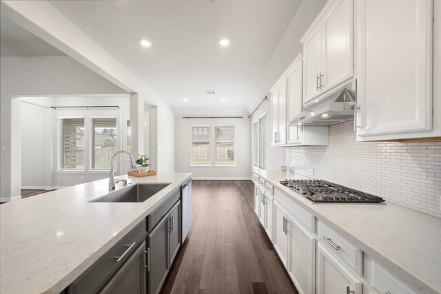 27130 Spanish Wind Ct, Magnolia, TX 77354 - kitchen featuring a sink, under cabinet range hood, stainless steel gas stovetop, white cabinetry, and tasteful backsplash