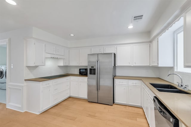13631 Balmore Cir, Houston, TX 77069 - kitchen with black appliances, a sink, washer / clothes dryer, tasteful backsplash, and white cabinetry