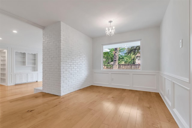 13631 Balmore Cir, Houston, TX 77069 - unfurnished dining area with a chandelier, light wood finished floors, a wainscoted wall, built in shelves, and a decorative wall
