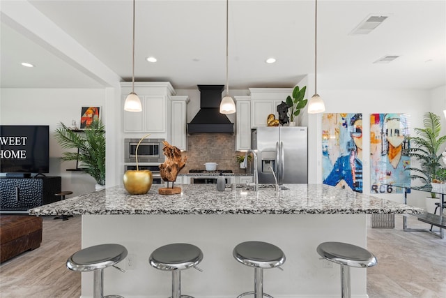1304 Veranda Mist, League City, TX 77573 - kitchen with appliances with stainless steel finishes, custom range hood, decorative backsplash, white cabinets, and stone counters