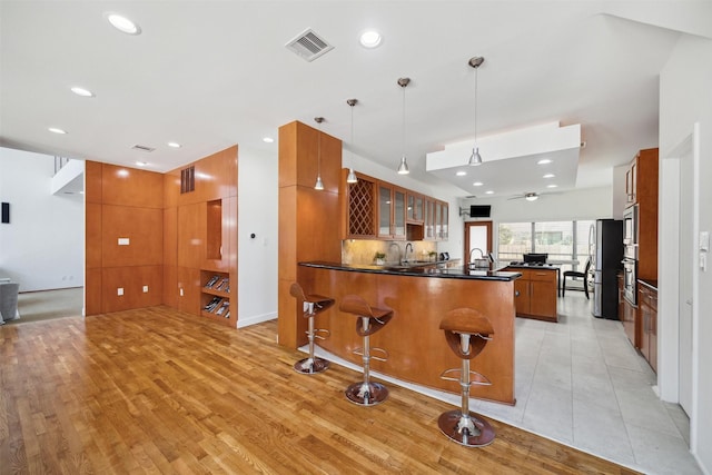 8003 Harbor Point Dr, Houston, TX 77071 - kitchen featuring a peninsula, glass insert cabinets, brown cabinets, dark countertops, and a breakfast bar