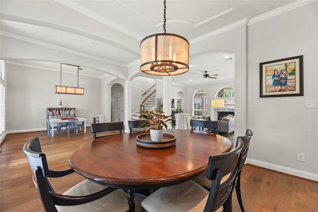 18818 Cypress Chateau Dr, Spring, TX 77388 - dining area featuring arched walkways, a chandelier, stairs, wood finished floors, and a fireplace