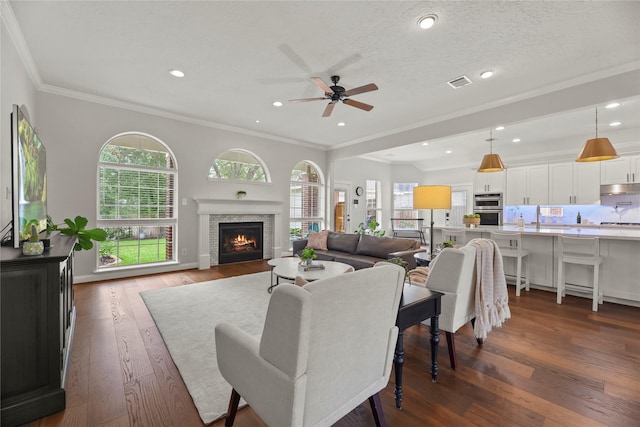 18818 Cypress Chateau Dr, Spring, TX 77388 - living room featuring ceiling fan, ornamental molding, dark wood-type flooring, a warm lit fireplace, and recessed lighting