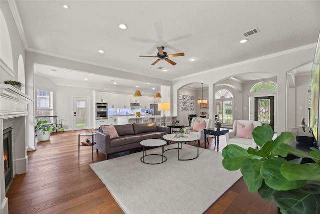 18818 Cypress Chateau Dr, Spring, TX 77388 - living room featuring arched walkways, a warm lit fireplace, a ceiling fan, crown molding, and wood finished floors