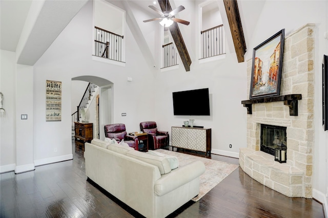 10727 Stone Isle Ct, Richmond, TX 77407 - living room featuring dark wood finished floors, a ceiling fan, arched walkways, baseboards, and a stone fireplace