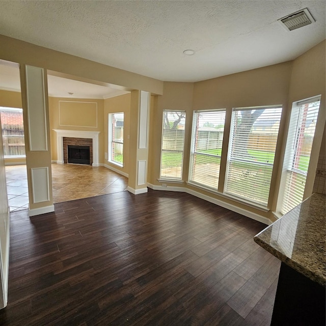 6118 Deep S Dr, Katy, TX 77449 - unfurnished living room featuring dark wood-style flooring, plenty of natural light, a fireplace, baseboards, and a textured ceiling