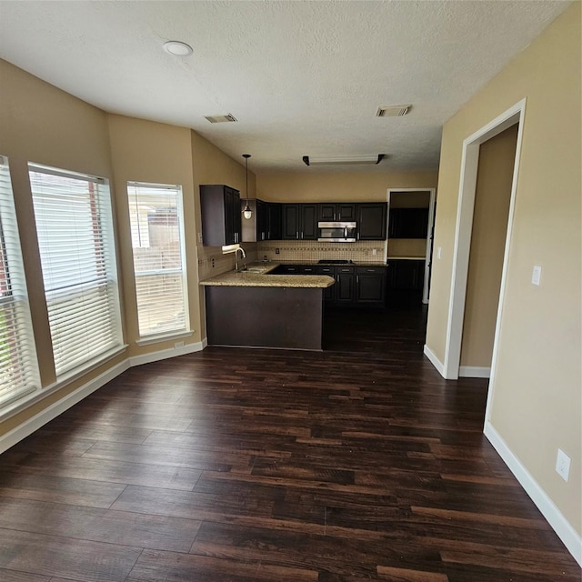 6118 Deep S Dr, Katy, TX 77449 - kitchen with dark wood-type flooring, a peninsula, stainless steel microwave, baseboards, and a textured ceiling