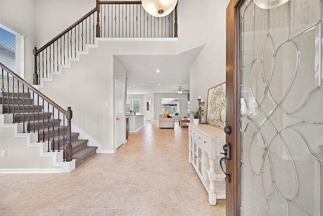 2708 Merlin Ln, Pearland, TX 77581 - foyer entrance with a towering ceiling, stairway, ceiling fan, light tile patterned floors, and baseboards