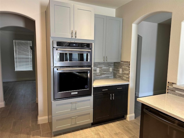 24811 Deep Coral Ct, Katy, TX 77494 - kitchen featuring stainless steel double oven, light wood-type flooring, dishwasher, tasteful backsplash, and arched walkways