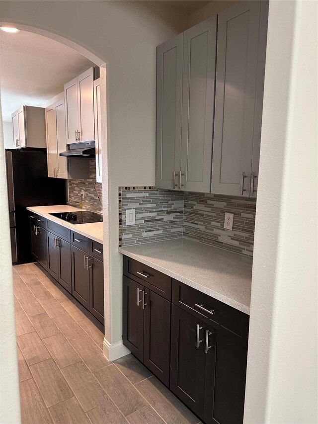 24811 Deep Coral Ct, Katy, TX 77494 - kitchen with under cabinet range hood, black electric cooktop, backsplash, and light countertops