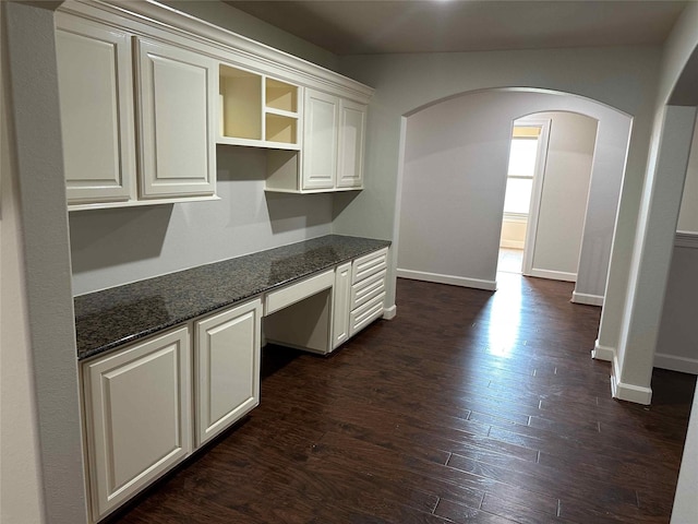 24811 Deep Coral Ct, Katy, TX 77494 - kitchen with arched walkways, dark wood-type flooring, baseboards, and dark stone countertops