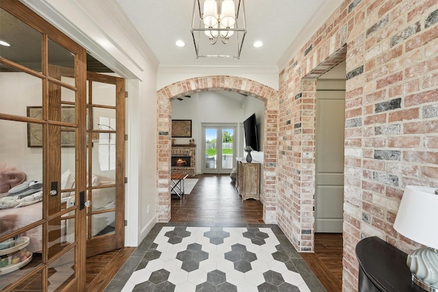 9343 Kai Dr, Beach City, TX 77523 - entryway with arched walkways, french doors, brick wall, a fireplace, and a chandelier