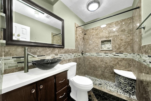 8030 Dodiewood Ln, Houston, TX 77086 - bathroom featuring tile walls, vanity, a tile shower, toilet, and a textured ceiling