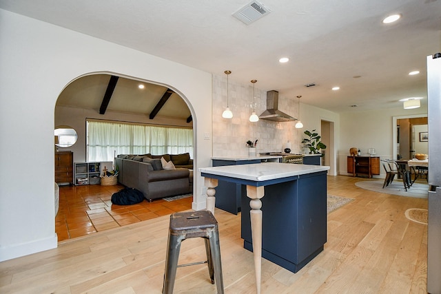 2735 Triway Ln, Houston, TX 77043 - kitchen with wall chimney range hood, arched walkways, light wood-type flooring, tasteful backsplash, and pendant lighting