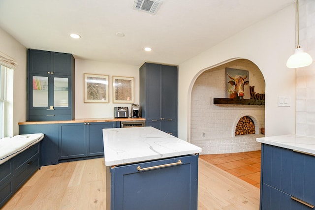 2735 Triway Ln, Houston, TX 77043 - kitchen with blue cabinetry, light wood-style floors, a fireplace, decorative light fixtures, and recessed lighting