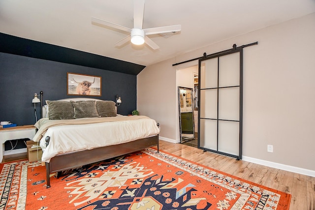 2735 Triway Ln, Houston, TX 77043 - bedroom featuring a barn door, light wood-style floors, baseboards, and ensuite bath