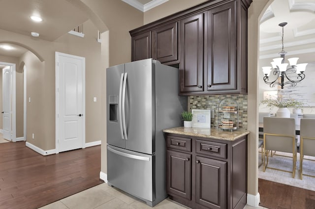 13518 Ambler Springs Dr, Tomball, TX 77377 - kitchen with stainless steel refrigerator with ice dispenser, arched walkways, dark brown cabinets, decorative backsplash, and ornamental molding