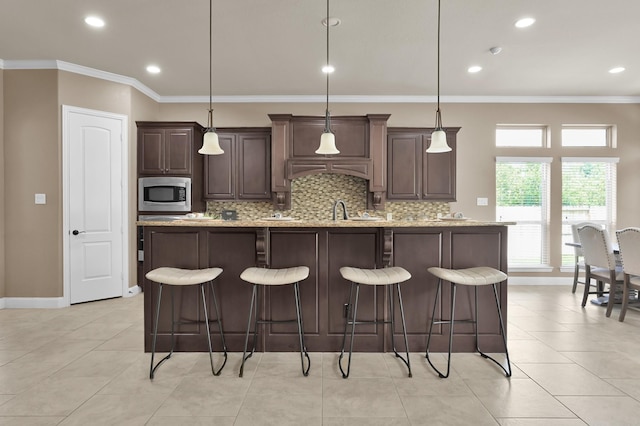 13518 Ambler Springs Dr, Tomball, TX 77377 - kitchen featuring stainless steel microwave, crown molding, backsplash, dark brown cabinetry, and recessed lighting