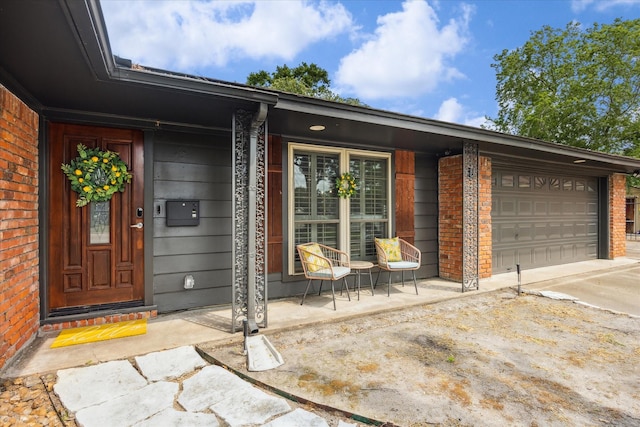 10228 Brinwood Dr, Houston, TX 77043 - property entrance featuring brick siding, a garage, concrete driveway, and a porch