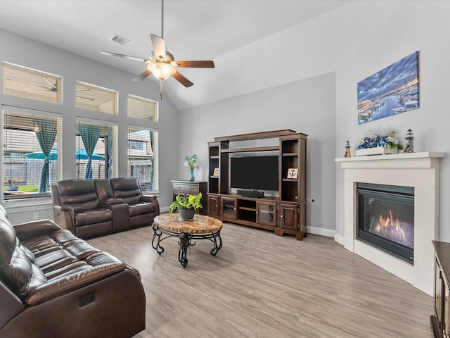 2314 Navo Ln, League City, TX 77573 - living area with ceiling fan, wood finished floors, a glass covered fireplace, lofted ceiling, and baseboards