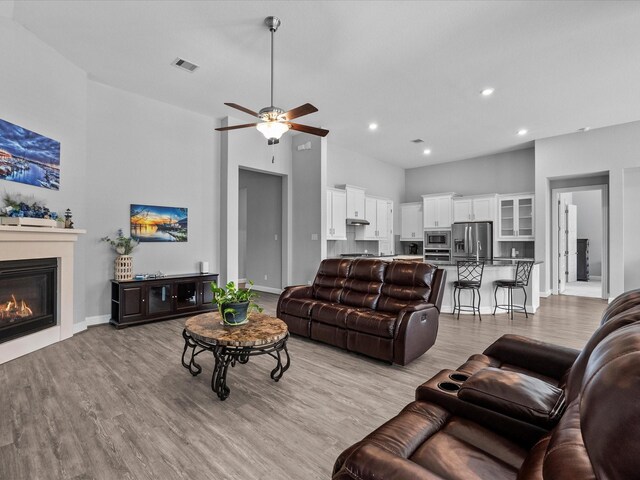 2314 Navo Ln, League City, TX 77573 - living room featuring a glass covered fireplace, light wood finished floors, baseboards, a ceiling fan, and recessed lighting