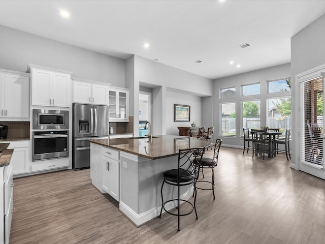 2314 Navo Ln, League City, TX 77573 - kitchen with appliances with stainless steel finishes, a sink, a center island with sink, a breakfast bar, and dark stone counters