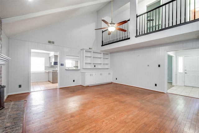15319 Paseo Del Rey Dr, Houston, TX 77083 - unfurnished living room with light wood-style flooring, ceiling fan, high vaulted ceiling, a fireplace, and baseboards