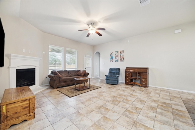 3707 Daintree Park Dr, Katy, TX 77494 - living area with a ceiling fan, arched walkways, light tile patterned flooring, a fireplace with raised hearth, and baseboards