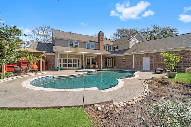 11407 Squiredale Dr, Houston, TX 77070 - rear view of property featuring a patio area, brick siding, a pool with connected hot tub, and a chimney