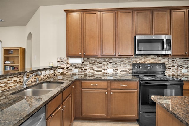 2602 Tacoma Springs Dr, Conroe, TX 77304 - kitchen with stainless steel appliances, a sink, tasteful backsplash, dark stone counters, and arched walkways