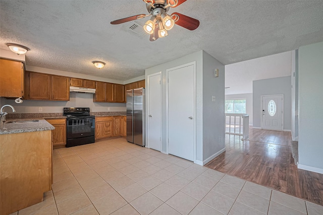 1806 Foxlake Dr, Houston, TX 77084 - kitchen with black / electric stove, freestanding refrigerator, a sink, under cabinet range hood, and brown cabinets