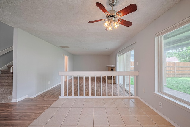 1806 Foxlake Dr, Houston, TX 77084 - empty room with a textured ceiling, light wood finished floors, ceiling fan, baseboards, and stairway